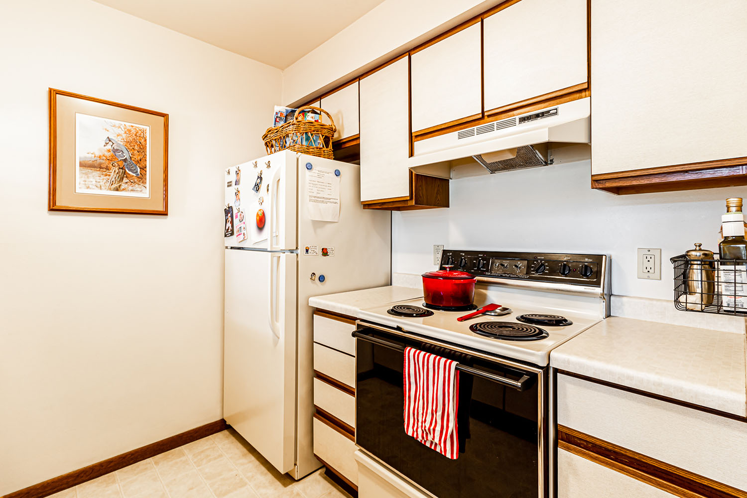 An apartment galley kitchen, view of the stove and fridge