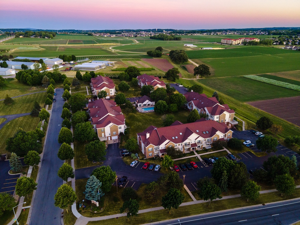Aerial shot of apartment complex grounds surrounded by farmland at dusk