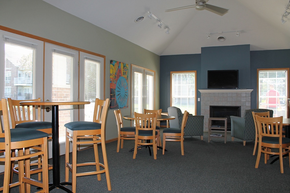 Clubhouse diningroom with tables and chairs and a fireplace with comfy chairs