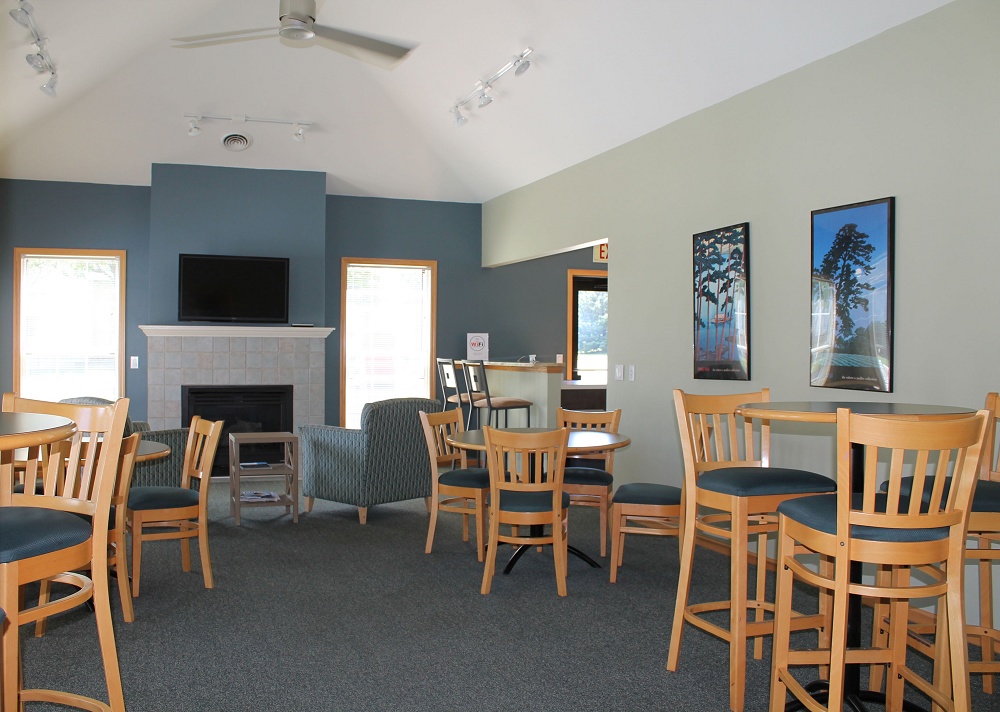 Clubhouse diningroom with tables and chairs and a fireplace with comfy chairs