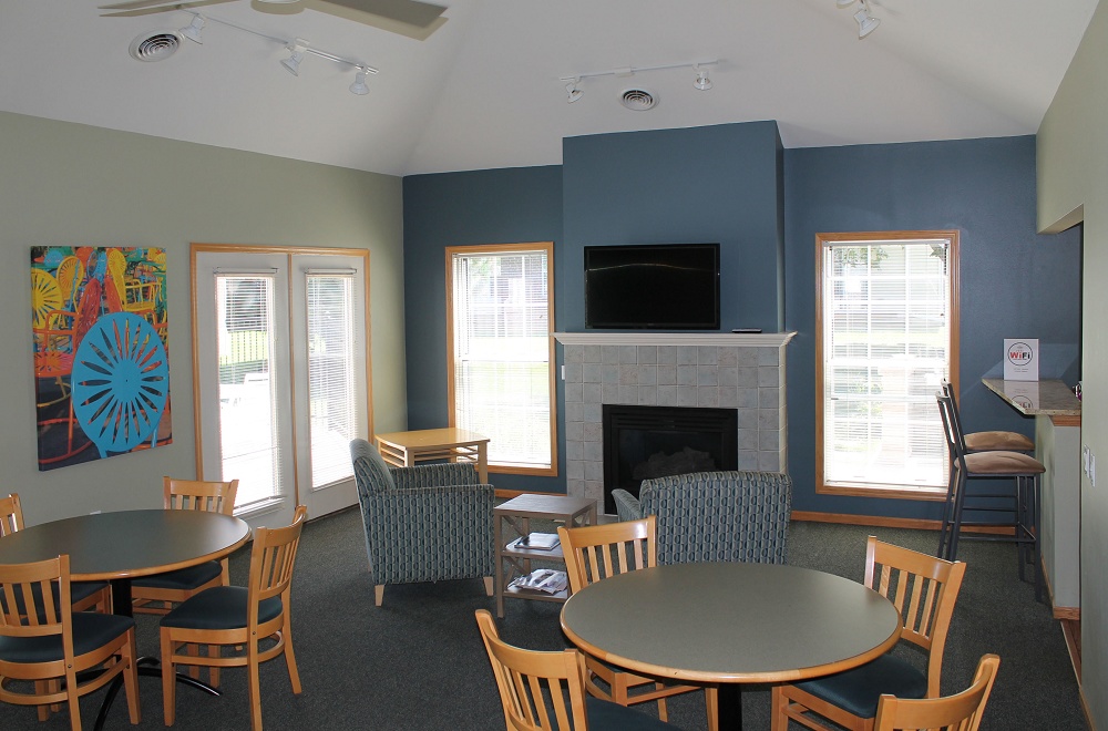 Clubhouse diningroom with tables and chairs and a fireplace with comfy chairs