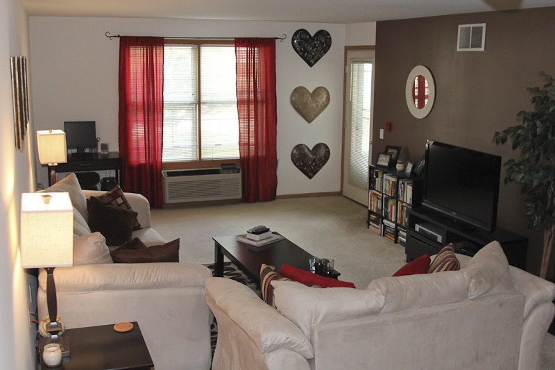 A living room with a couch on the left with two end tables and lamps, a loveseat on the right, and a tv against the wall