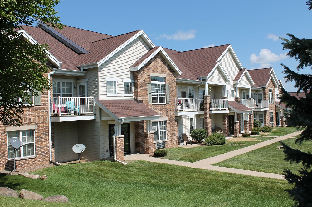 Apartment complex and lawn, framed by pine trees