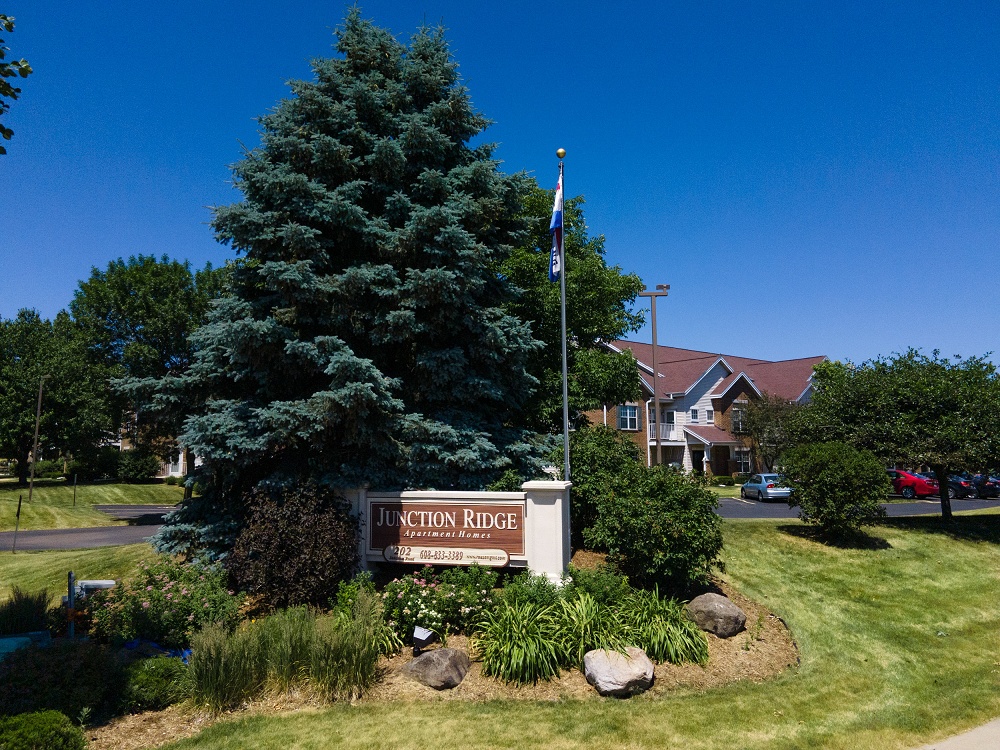 Junction Ridge apartment complex sign surrounded by pine trees on a sunny day