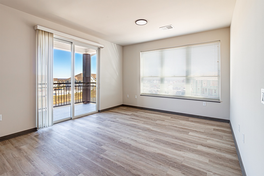 An empty apartment with a door leading to a balcony