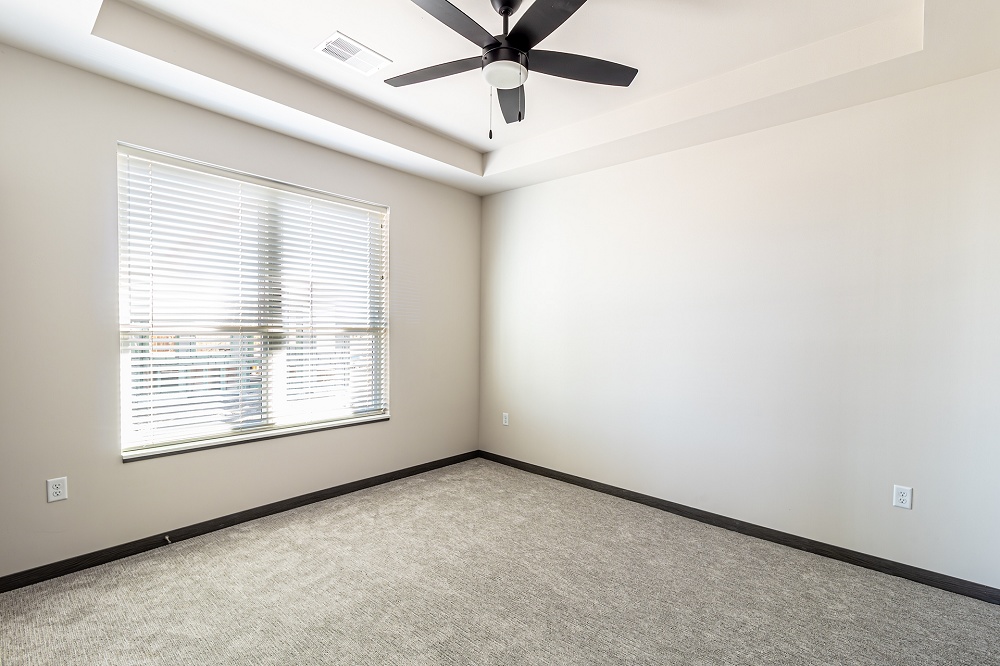 An empty apartment bedroom with a ceiling fan