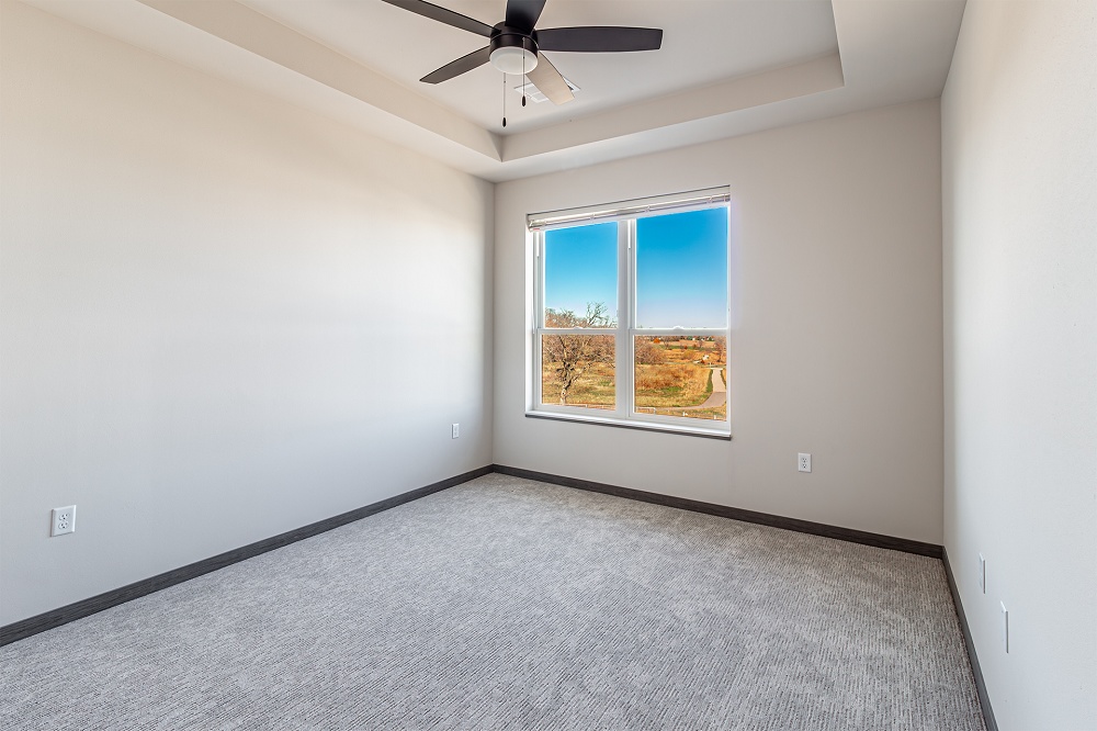 An empty apartment bedroom with a ceiling fan