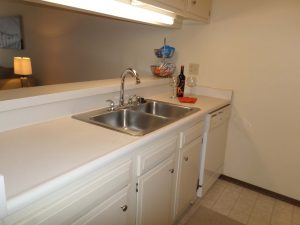 Kitchen counter with sink and wine bottle and two glasses next to it