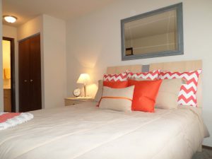 A bed with a mirror above the headboard and side table with a lamp on it