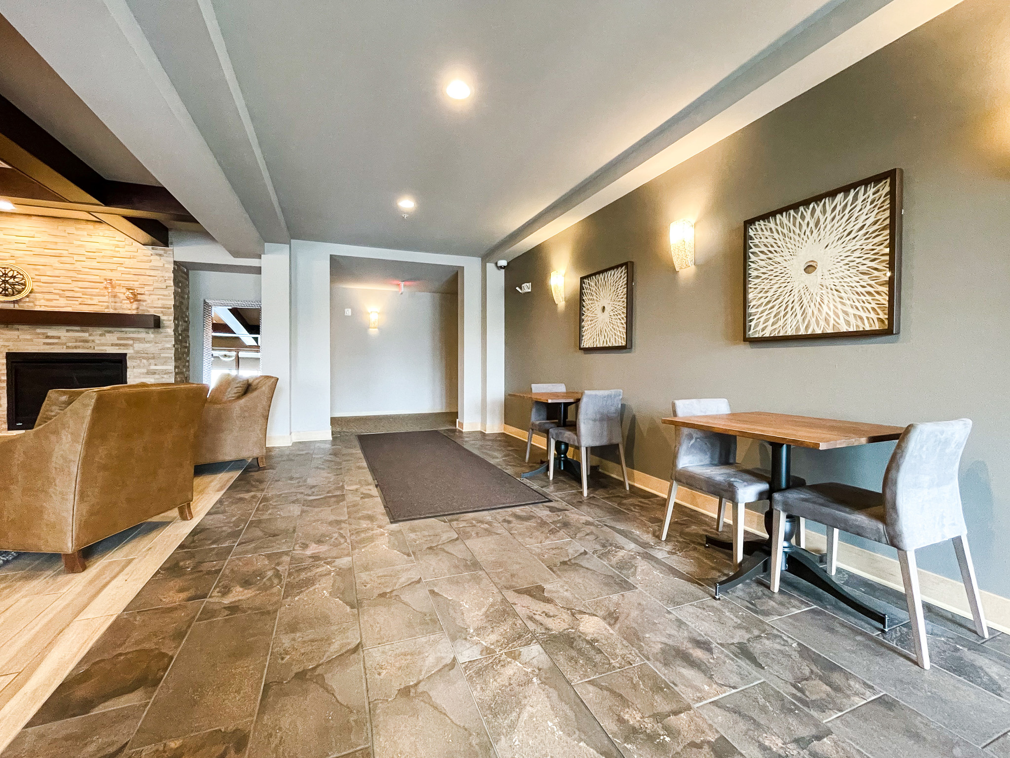 Hallway area with two tables with chairs and art on the left wall