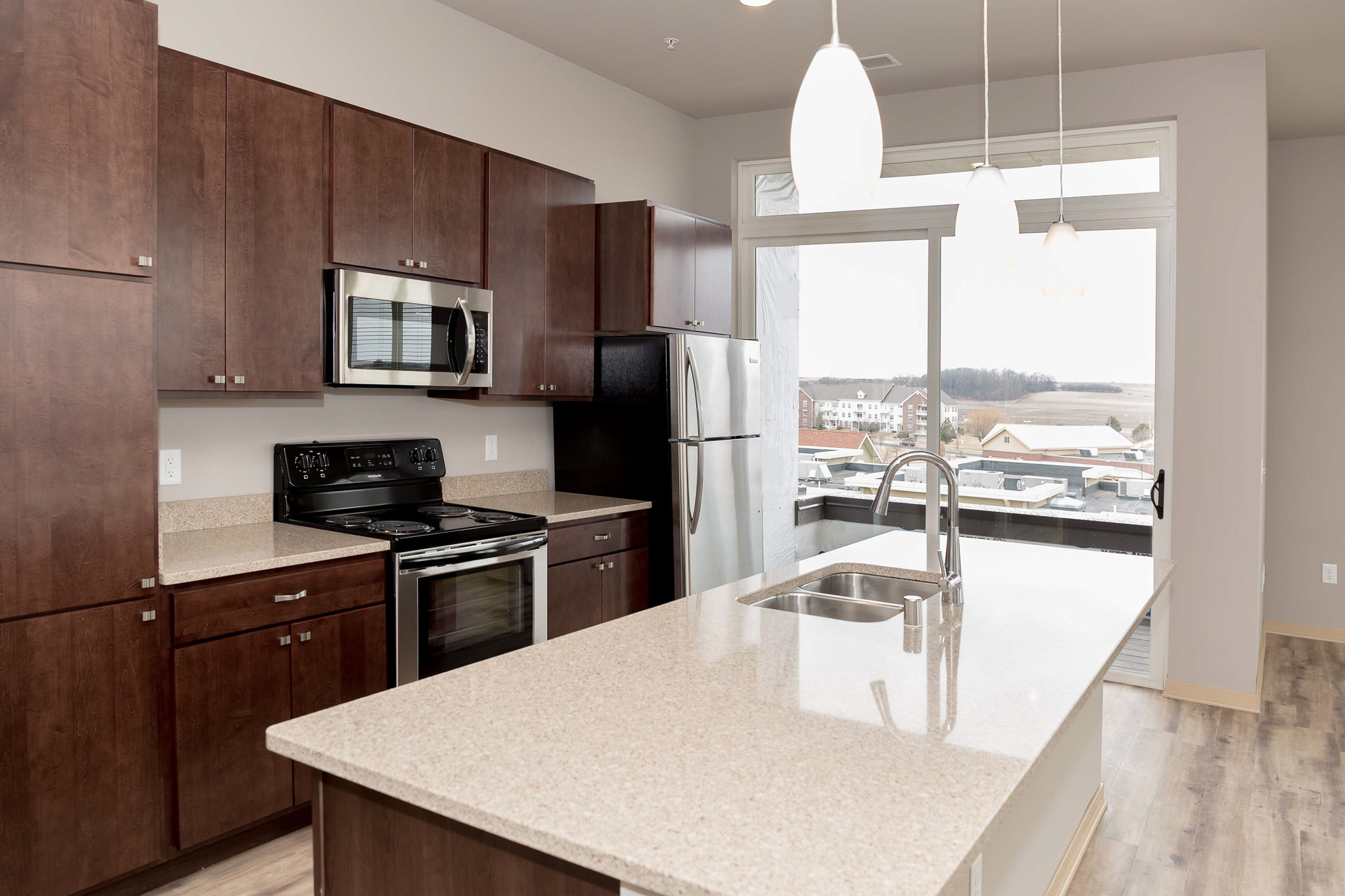 Open kitchen area with door to balcony and island with sink in the middle