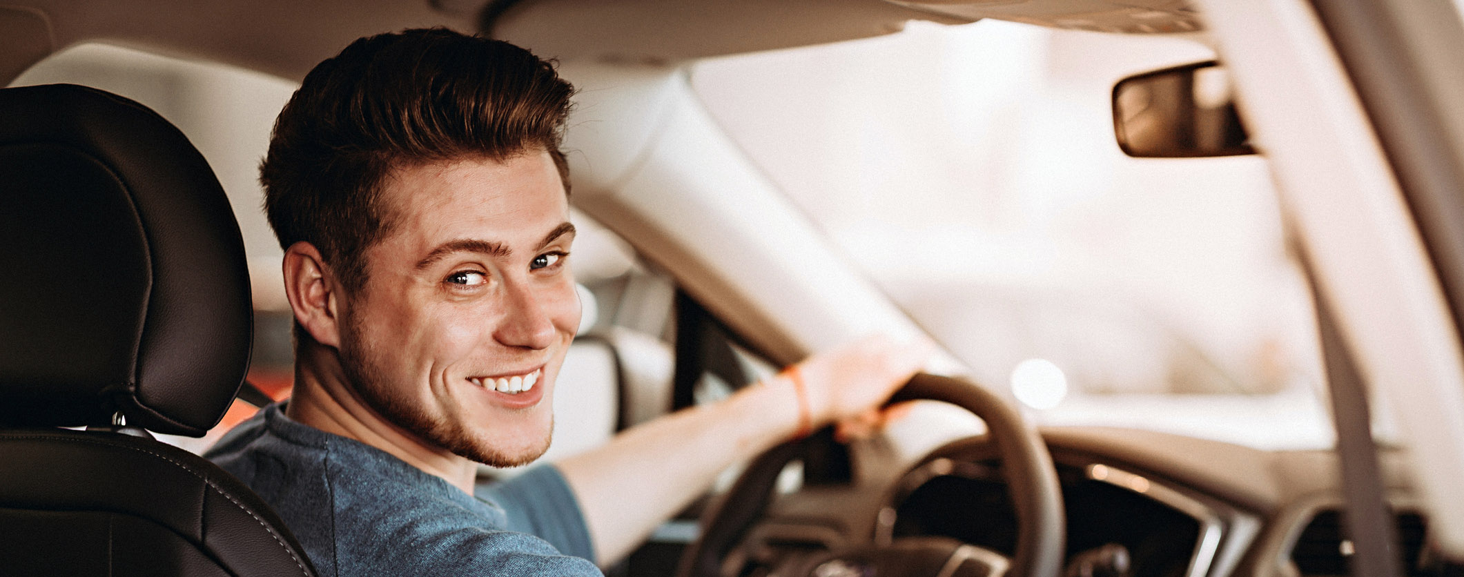 Happy young driver behind the wheel of a car. Buying a car and driving concept