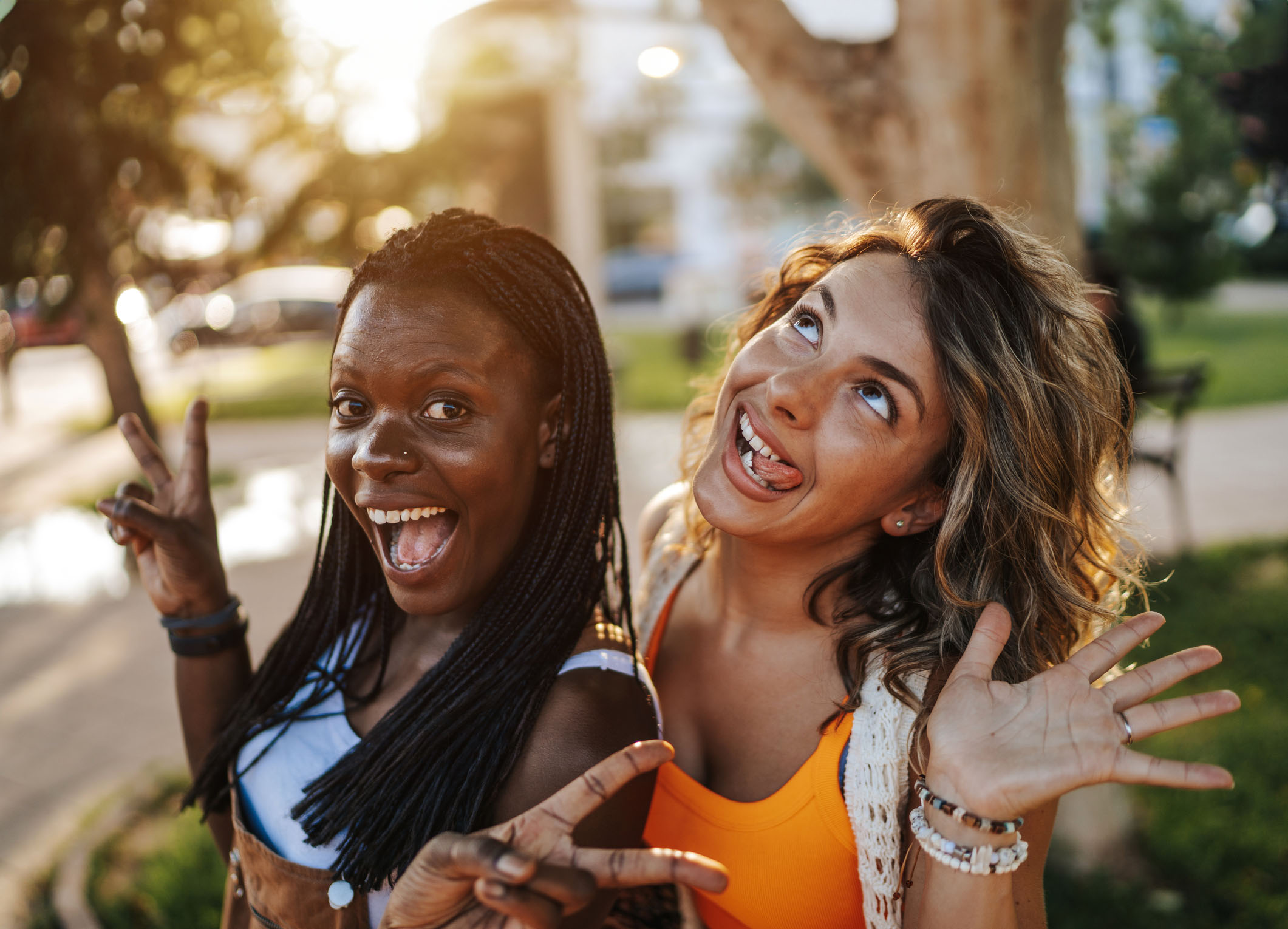 Happy young female friends having fun, posing and making faces in the city on sunny summer day