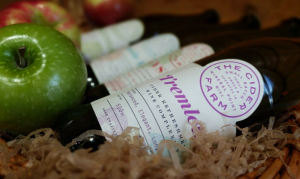 Four bottles of cider and an apple nestled in a gift box